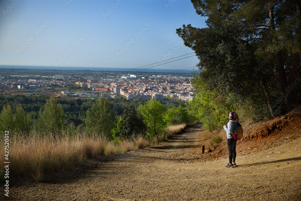 Woman with sportswear and backpack observing the city from above. Woman with sportswear and backpack observing the city from above.