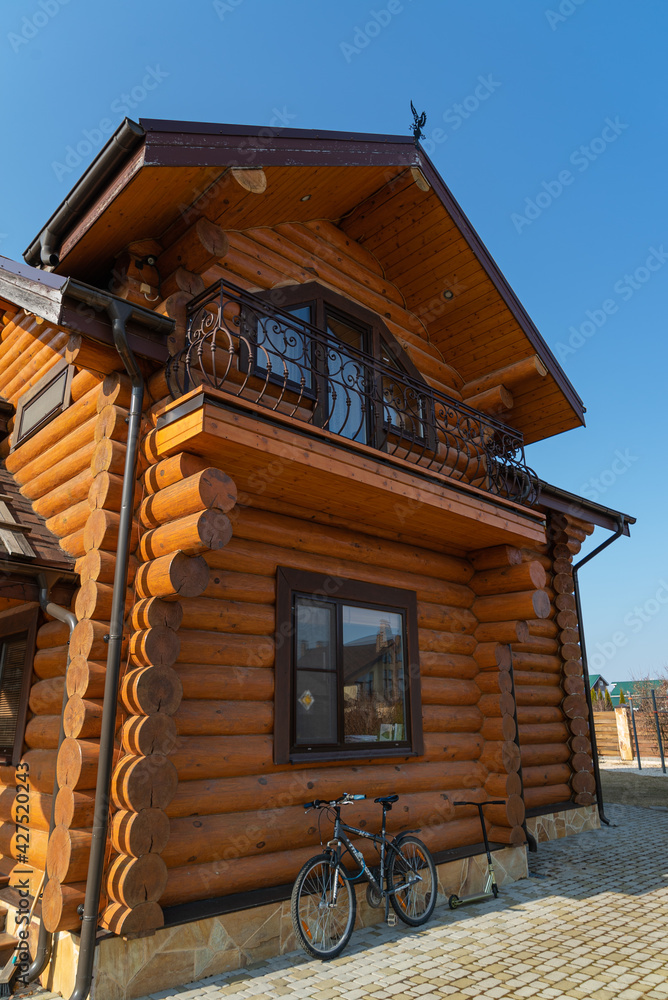 Wooden house from a honey-colored solid bar on the background of a spring garden