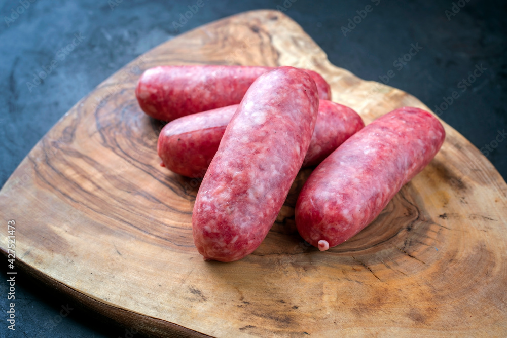 Traditional Italian raw salsiccia fresco meat sausage offered as close-up on a rustic wooden cutting board Traditional Italian raw salsiccia fresco meat sausage offered as close-up on a rustic wooden cutting board