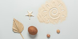 Summer beach composition. Drawing of the sun on the sand, coconut, starfish, seashells and dry palm leaf on a gray background. Top view, flat lay. Creative layout. Banner