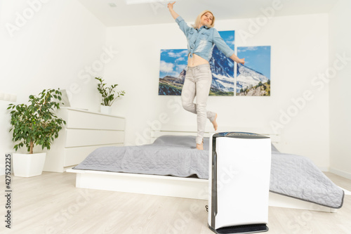 air purifier in room for clean and fresh air with woman stretching hands and relax in background