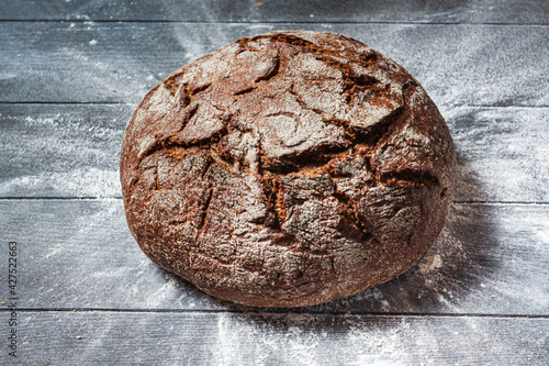 Rye bread and flour on a dark wooden table.