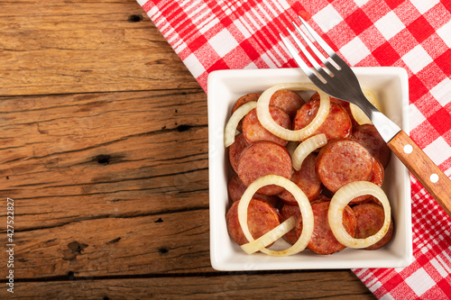 Sliced ​​calabrese sausage with onion on wooden background. photo