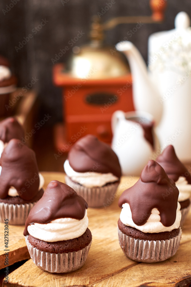 Chocolate cupcakes with cherries, cream and chocolate icing. Side view. Wooden background.