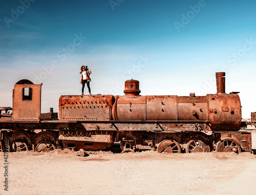 Girl on rusty steam train near Uyuni in Bolivia. Cemetery trains. photo