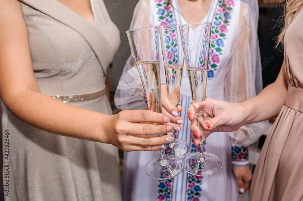 Glasses with white wine in the hands of the girls. Wine glasses in the hands of the bride and bridesmaids