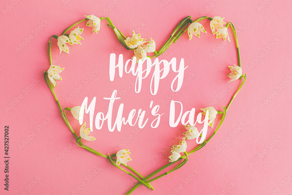 Happy mother's day. Happy mother's day text and floral heart flat lay on pink paper. Stylish floral greeting card. Handwritten lettering on heart made of spring flowers on pink. Mothers day - obrazy, fototapety, plakaty 