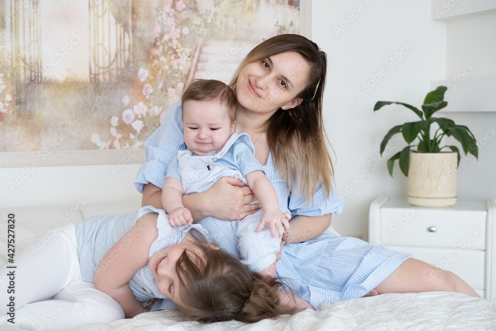smiling mother with baby boy son and funny small preschooler daughter have fun at home smiling mother with baby boy son and funny small preschooler daughter have fun at home