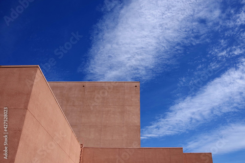 Partial view of a theater building at a public high school under blue sky with some clouds