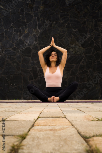 Young woman sitting in yoga posture. With arms above the head. Meditation