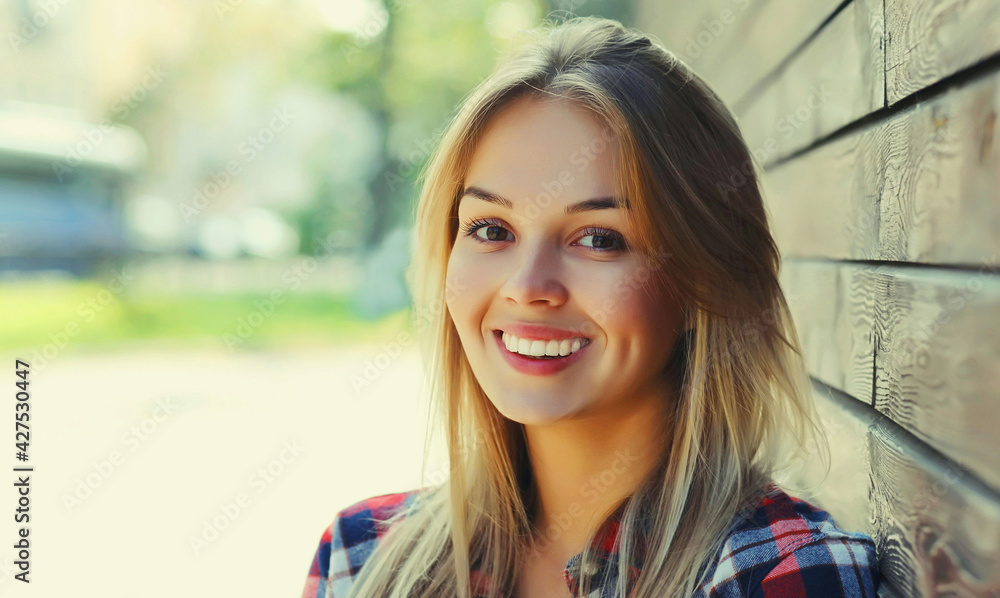 Portrait close up of beautiful happy smiling young blonde woman in a city