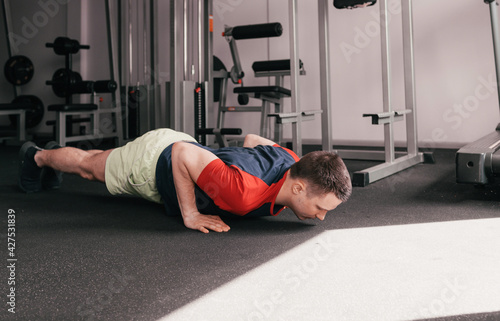 a young guy does push-ups from the floor in the gym during a workout. healthy lifestyle. intensive training