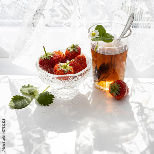 Cup of tea and wild strawberries on a white lace background