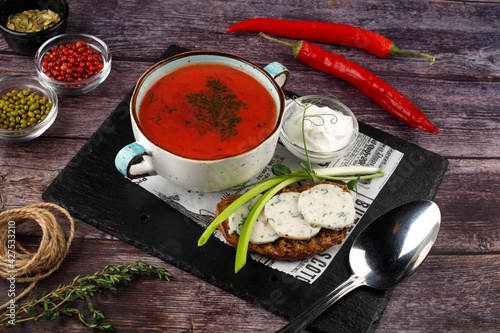 Traditional Ukrainian Russian borscht in a plate. A plate of red beet borscht on a dark table. Beetroot garden Top view.