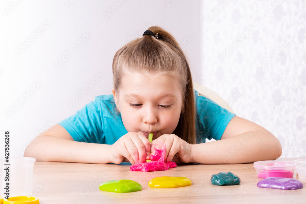 A blonde child blows a slime bubble. Play a slime toy. Making slime at home A blonde child blows a slime bubble. Play a slime toy. Making slime at home
