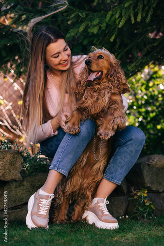 Cheerful girl holding her dog and looking at him. Smiling young