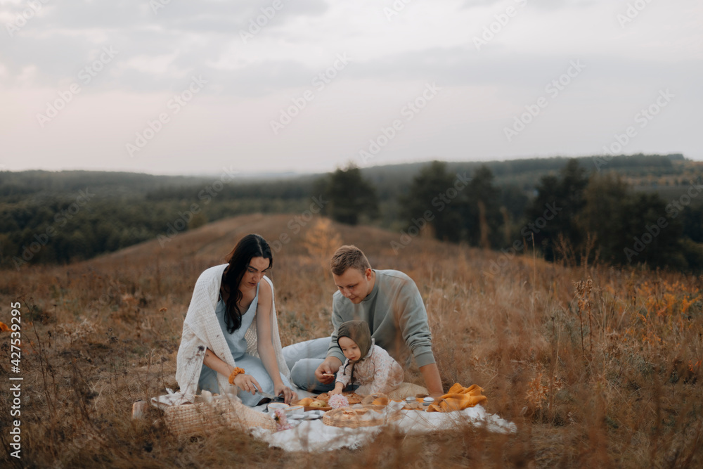 young happy family outdoors. family picnic on the hill in the forest. a young family is having dinner on the mountain. copy space on top