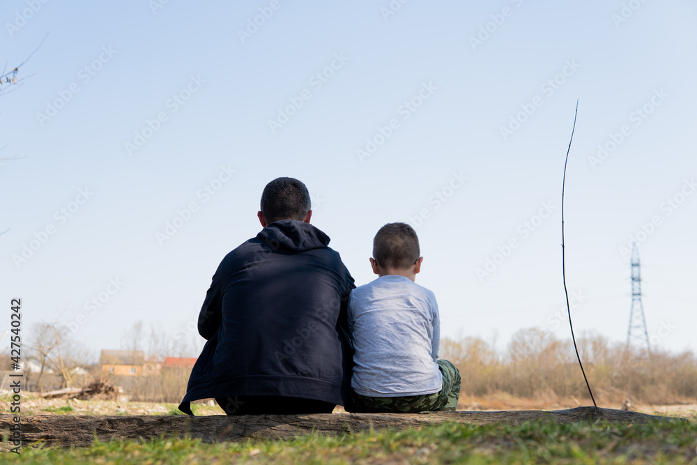 father with son sitting in nature