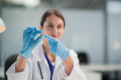 Presentation of a new antiviral drug. A female doctor prescribes treatment to a patient and holds a capsule of medicine in her hand