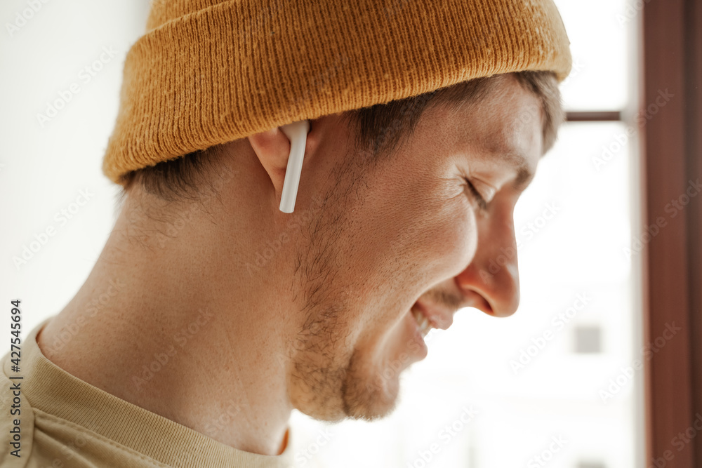 Obraz premium Close up young man traveler listening to music in AirPods in hotel room on summer vacation