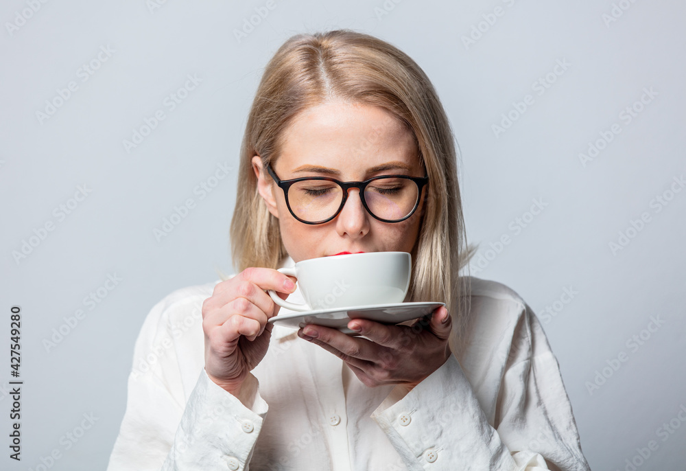 Portrait of beautiful blonde in white shirt with cup of coffee on white background Portrait of beautiful blonde in white shirt with cup of coffee on white background