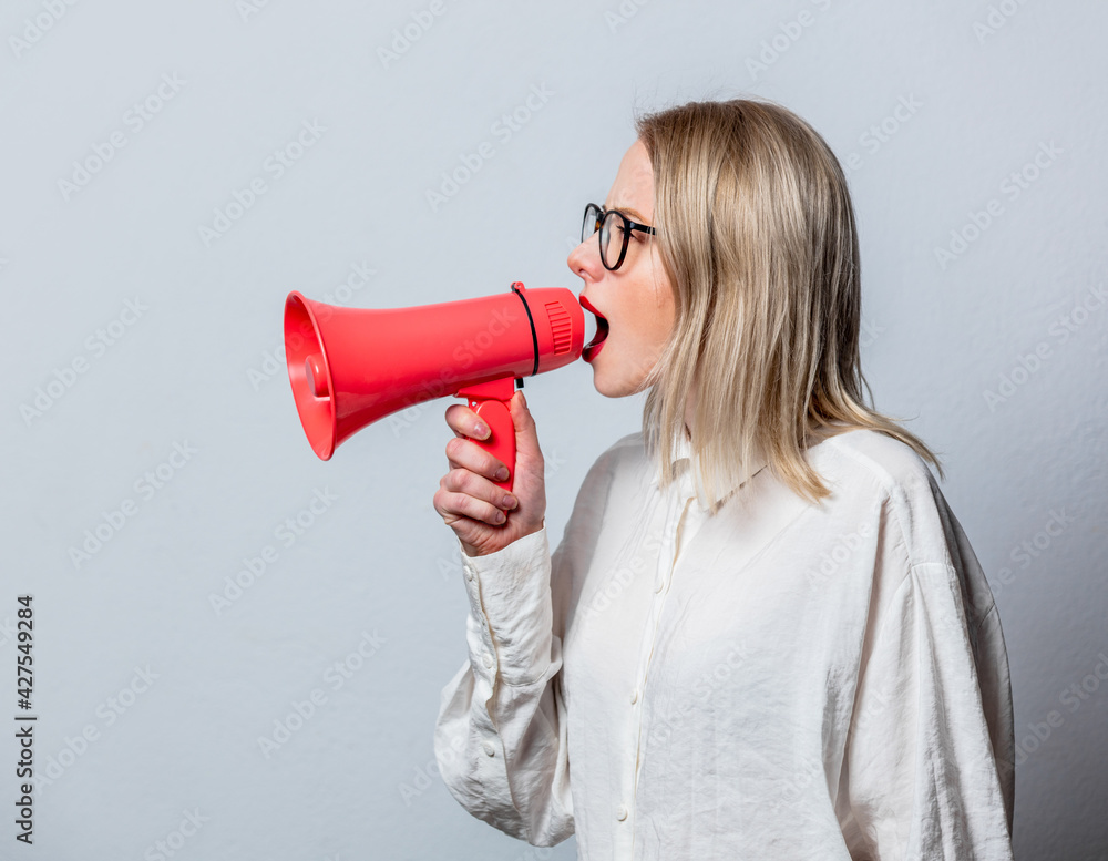 Portrait of beautiful blonde in white shirt with loudspeaker on white background Portrait of beautiful blonde in white shirt with loudspeaker on white background
