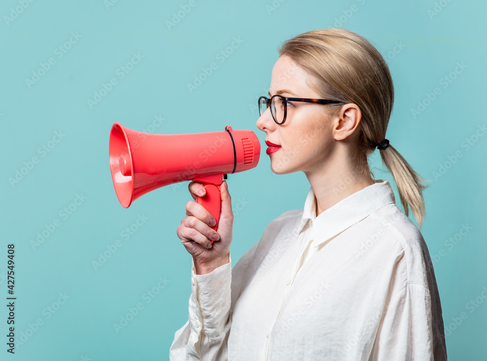 Portrait of beautiful blonde in white shirt with loudspeaker on blue background Portrait of beautiful blonde in white shirt with loudspeaker on blue background