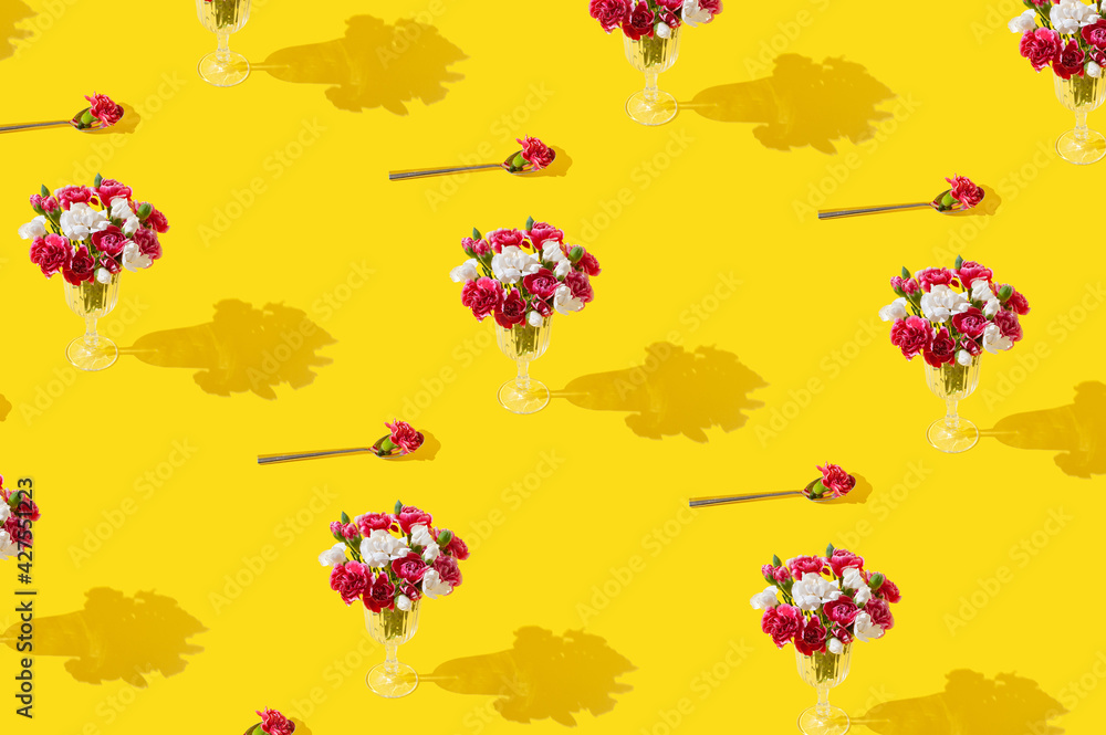 Spring flowers in wine glass on bright yellow background.