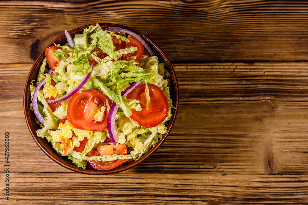 Vegan salad with savoy cabbage, tomatoes and onion in a ceramic bowl. Top view Vegan salad with savoy cabbage, tomatoes and onion in a ceramic bowl. Top view