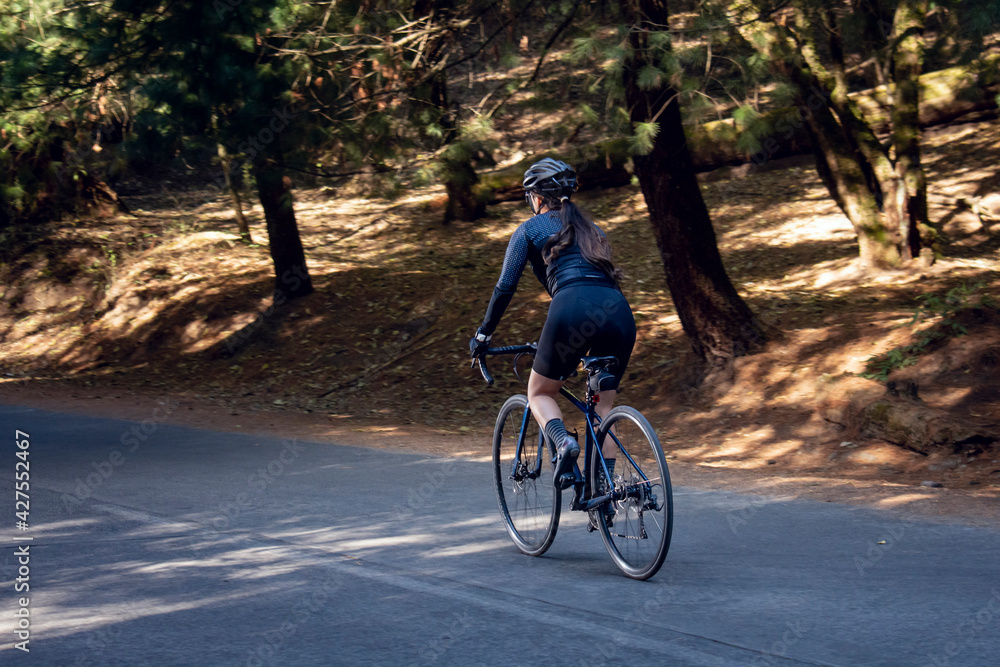 Mujer en bicicleta de pista en una carretera en medio del bosque. concepto de deporte al aire libre. 