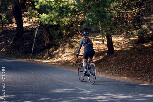 Mujer en bicicleta de pista en una carretera en medio del bosque. concepto de deporte al aire libre. 