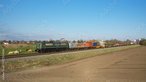 Elektrische Güterzuglokomotive 151 124 fährt mit ihrem Containerzug an landwirtschaftlichen Anwesen zwischen München-Aubing und Puchheim vorbei © Andreas