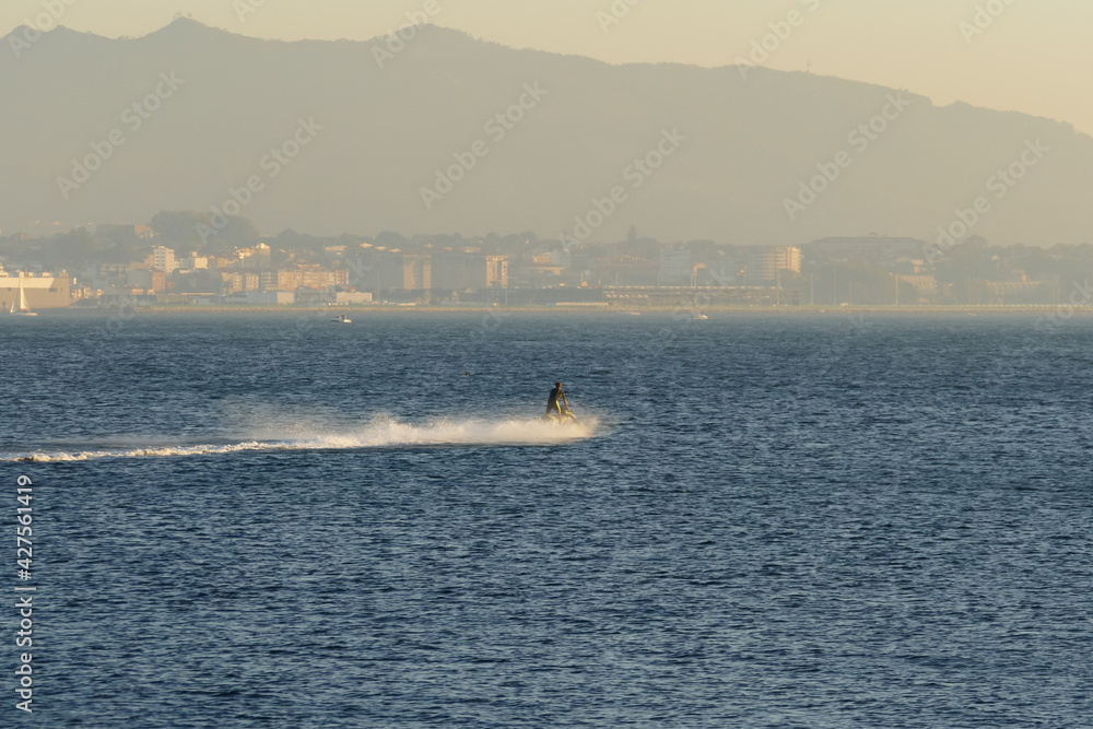jet ski furrows the sea with the city in the background
