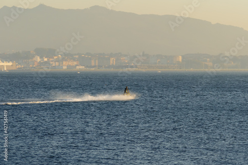 jet ski furrows the sea with the city in the background