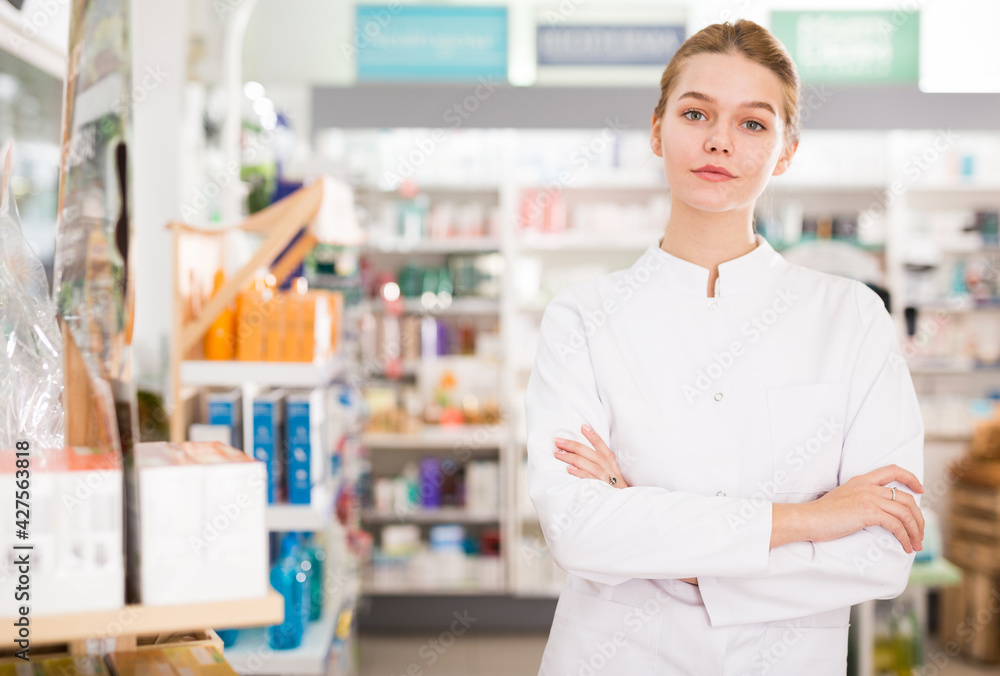 Portrait of young positive female pharmacist in modern drugstore
