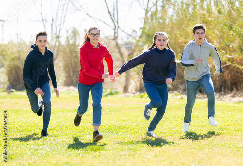 Cheerful teenagers are jogging together in the park and having fun