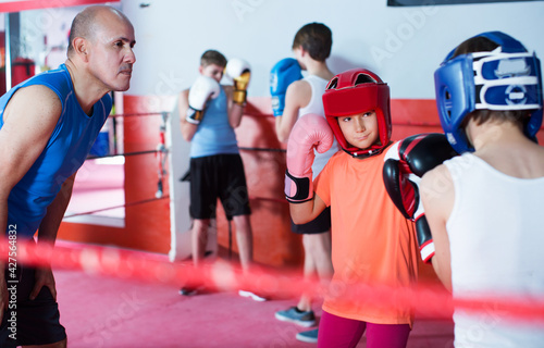 Glad teenage boxer sparring on the ring in boxing hall