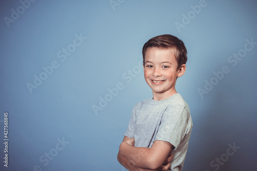 cool, young boy with grey t-shirt is posing in front of blue background in the studio