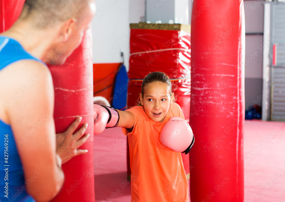 Positive young girl with boxing gloves posing in defended stance
