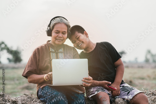 The  happy senior woman and grandson using laptop outdoor concept