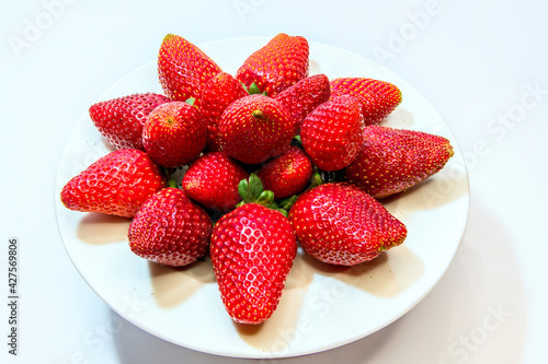 Red garden strawberry on the white kitchen saucer