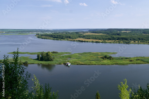 Panoramic view of river bend with island, boat and wharf