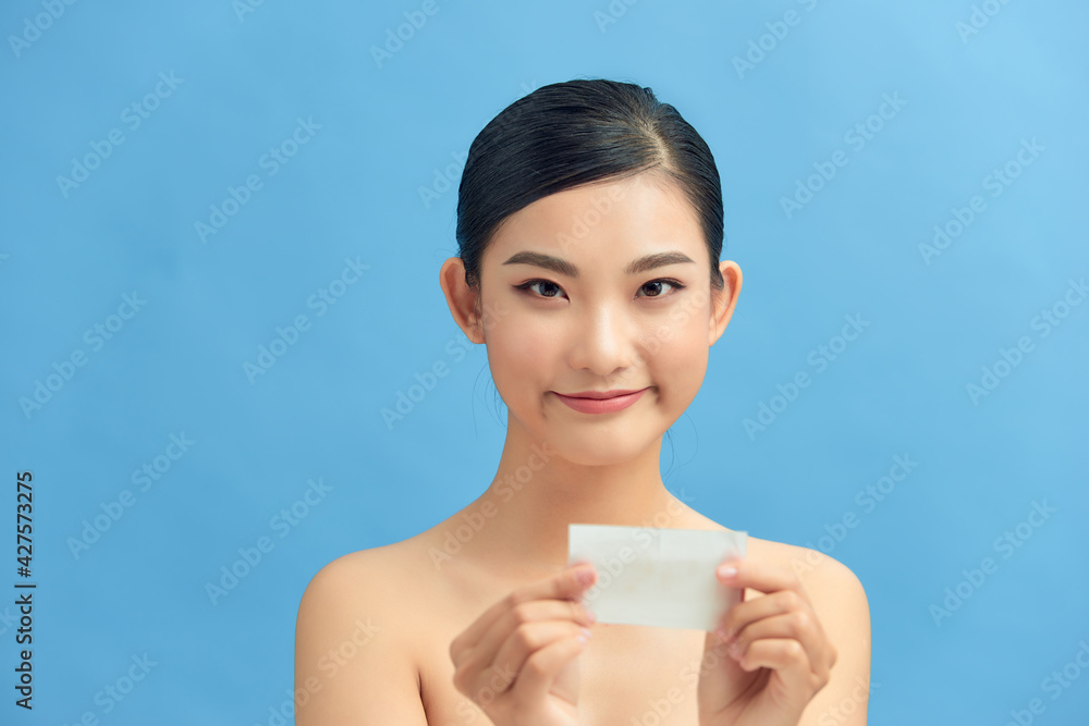 Women with oily skin using oil absorbing sheet on her face Women with oily skin using oil absorbing sheet on her face