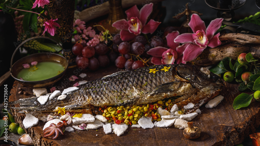 Still life in old masters style with fish, glass of wine, old dishes, fruits. The concept of a richly decorated table.