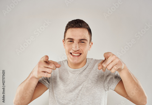 A cheerful man in a white T-shirt gestures with his hands emotions close-up