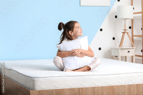 Morning of little girl sitting on bed with comfortable mattress photo
