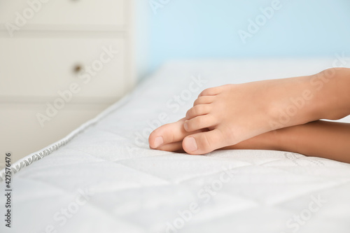 Feet of little girl sleeping on comfortable mattress, closeup