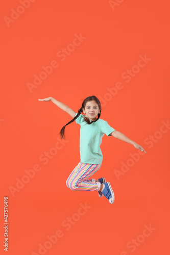Jumping little girl on color background