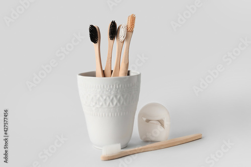 Holder with tooth brushes and floss on white background