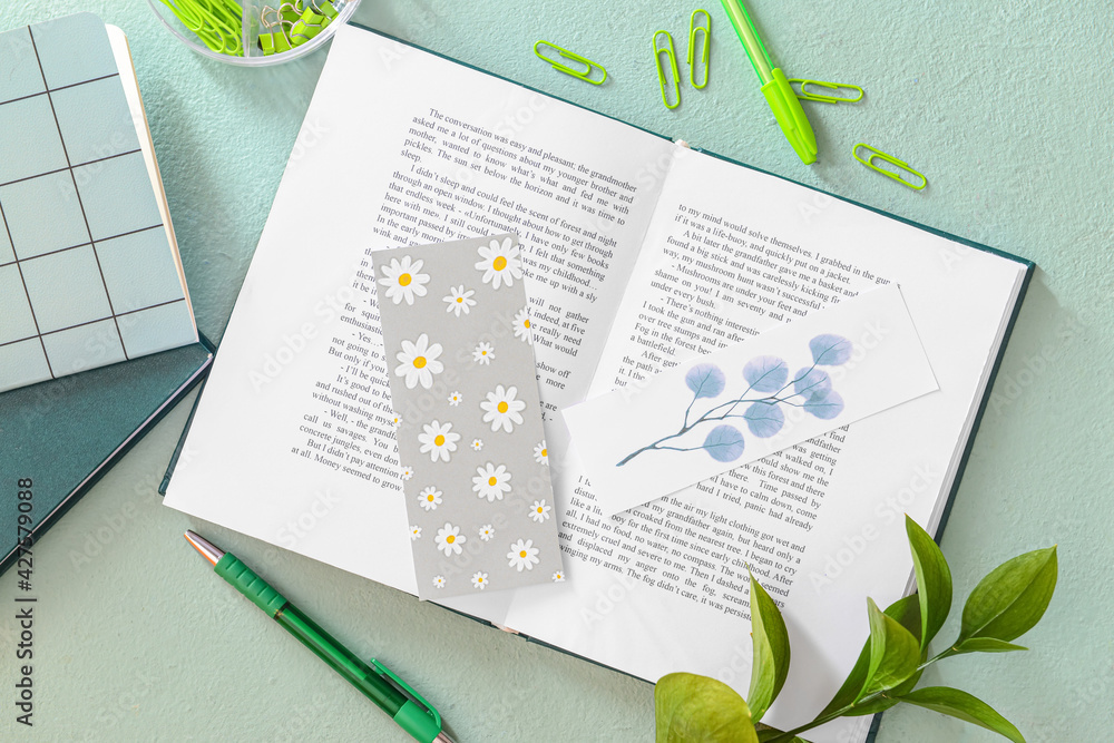 Book with bookmarks and stationery on color background - obrazy, fototapety, plakaty 